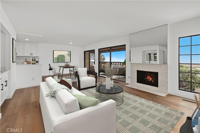 living area featuring a high end fireplace, wood finished floors, and plenty of natural light