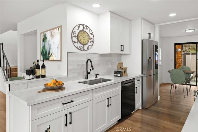 kitchen featuring stainless steel fridge with ice dispenser, a sink, light wood-type flooring, black dishwasher, and tasteful backsplash