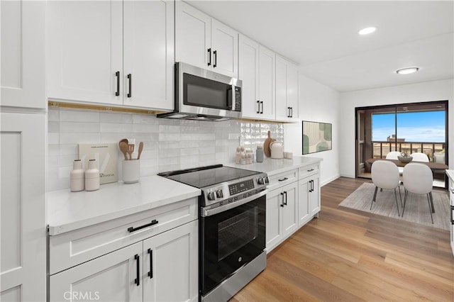 kitchen featuring decorative backsplash, white cabinetry, light wood finished floors, and stainless steel appliances