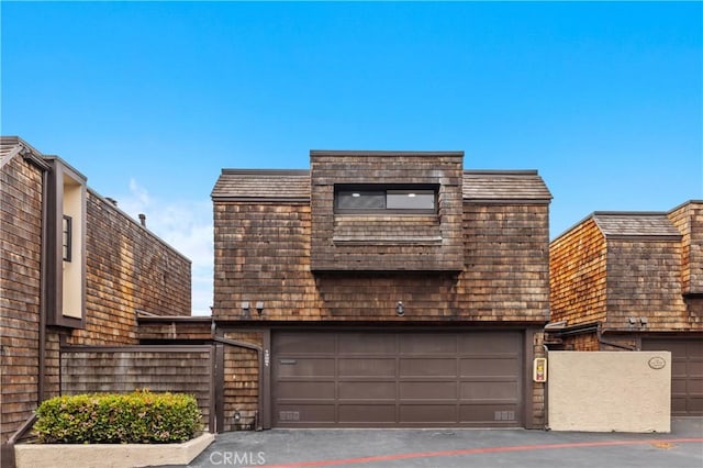 view of front facade with driveway, fence, and a garage