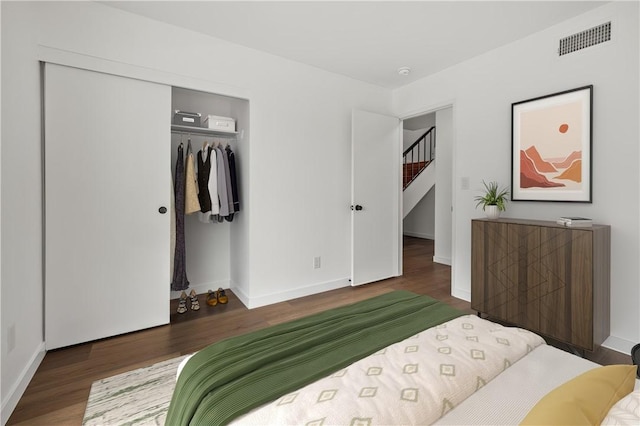 bedroom featuring baseboards, wood finished floors, visible vents, and a closet