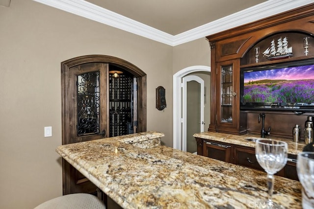 bar featuring arched walkways, indoor bar, and ornamental molding