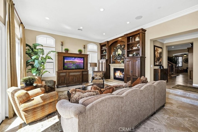 living room featuring visible vents, a glass covered fireplace, recessed lighting, and ornamental molding