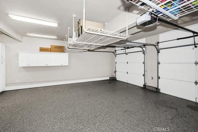 garage featuring a garage door opener and baseboards