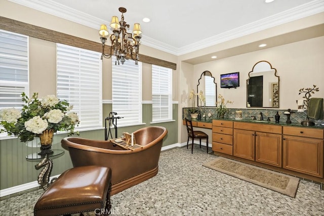 full bath featuring vanity, a freestanding tub, an inviting chandelier, baseboards, and ornamental molding