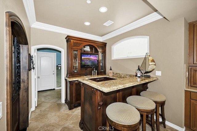 bar featuring indoor wet bar, visible vents, a sink, and crown molding