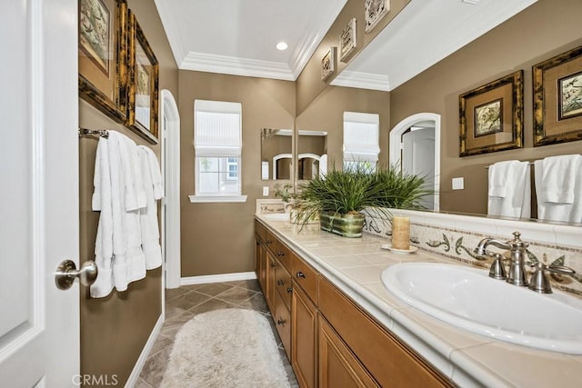 full bath with marble finish floor, double vanity, a sink, crown molding, and baseboards