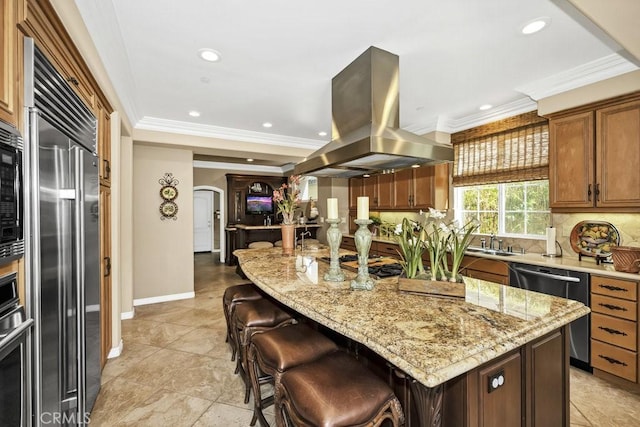kitchen featuring light stone counters, a center island, decorative backsplash, island exhaust hood, and stainless steel appliances