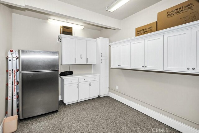 kitchen with white cabinets, freestanding refrigerator, and light countertops