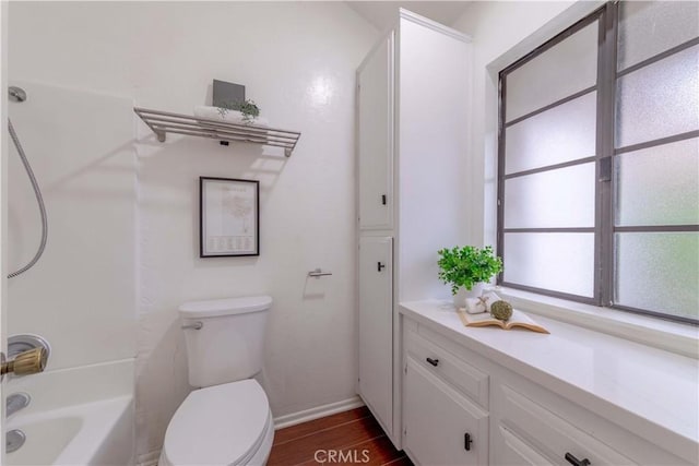 bathroom featuring toilet, shower / bathing tub combination, wood finished floors, and baseboards