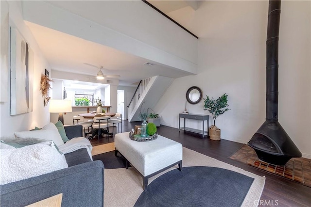 living room with stairs, a wood stove, and wood finished floors