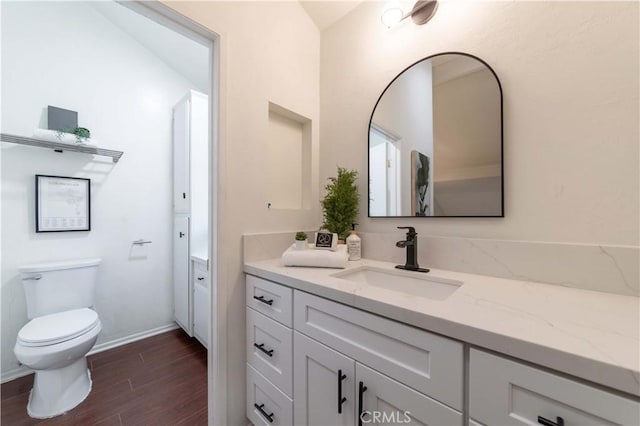 bathroom featuring toilet, vanity, wood finished floors, and baseboards