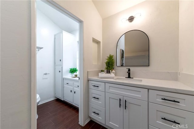 bathroom featuring toilet, wood finished floors, vanity, and lofted ceiling
