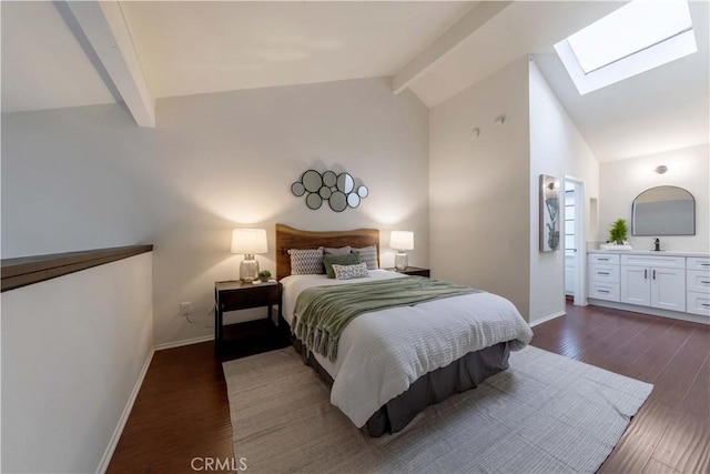 bedroom with baseboards, a sink, lofted ceiling with skylight, ensuite bath, and dark wood-type flooring