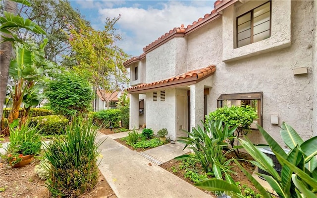 property entrance featuring a tiled roof and stucco siding