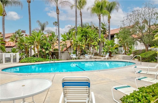 community pool with a patio area and fence