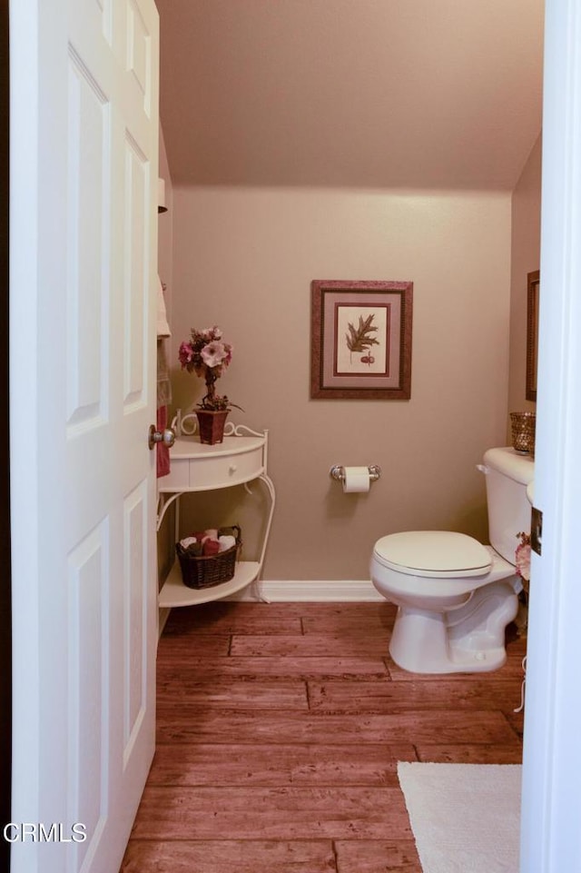 bathroom with baseboards, toilet, and wood finished floors