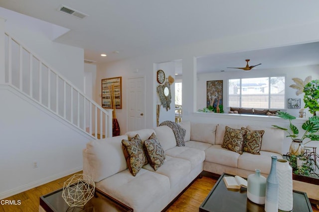 living room with visible vents, baseboards, stairs, wood finished floors, and a ceiling fan