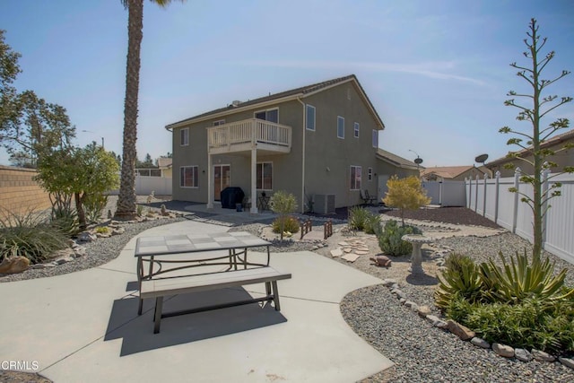rear view of house with a balcony, stucco siding, a fenced backyard, and a patio area