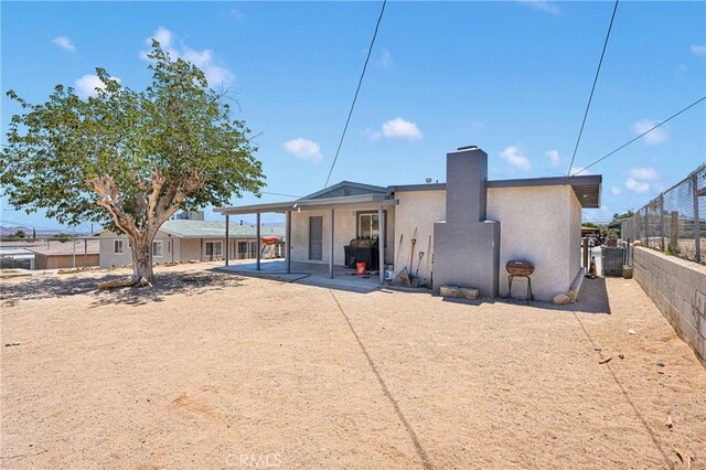 929 E Elizabeth St, Barstow, CA 92311 - rear view of property with stucco siding, a chimney, a fenced backyard, and a patio area