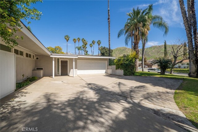 3540 Watkins Dr, Riverside, CA 92507 - view of front facade featuring concrete driveway, stucco siding, fence, a mountain view, and a garage