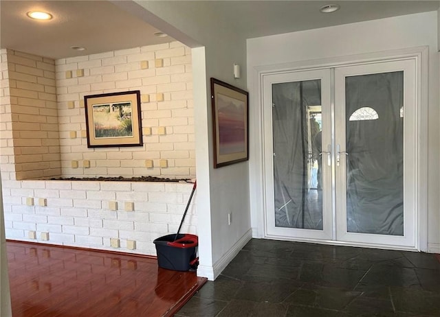 interior space with baseboards, french doors, recessed lighting, and brick wall