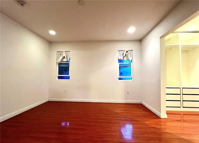 empty room with baseboards, wood finished floors, and recessed lighting
