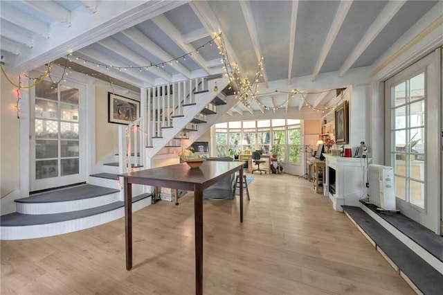 dining room with stairway, an inviting chandelier, light wood finished floors, and beam ceiling