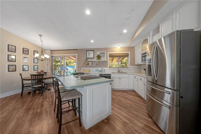 kitchen featuring light countertops, white cabinets, a sink, appliances with stainless steel finishes, and a wealth of natural light