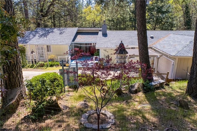 view of front of house featuring a garage, a shingled roof, fence, and a chimney