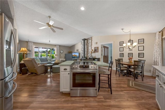 kitchen with a textured ceiling, vaulted ceiling, ceiling fan with notable chandelier, open floor plan, and stainless steel appliances