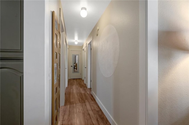 corridor with baseboards and wood finished floors