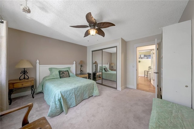 bedroom featuring ceiling fan, a closet, a textured ceiling, and light colored carpet