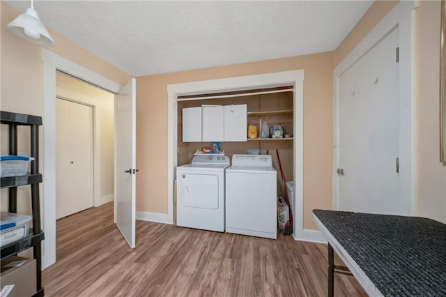 laundry room featuring baseboards, light wood-style flooring, cabinet space, and washing machine and clothes dryer