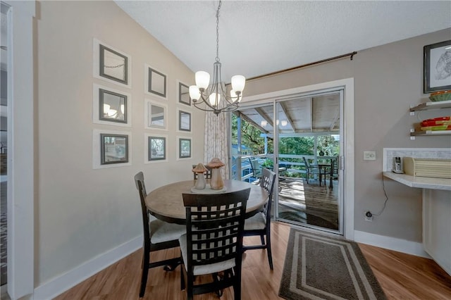 dining area featuring baseboards, wood finished floors, and a notable chandelier