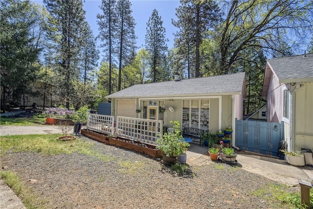 view of front of house featuring roof with shingles, fence, and a porch