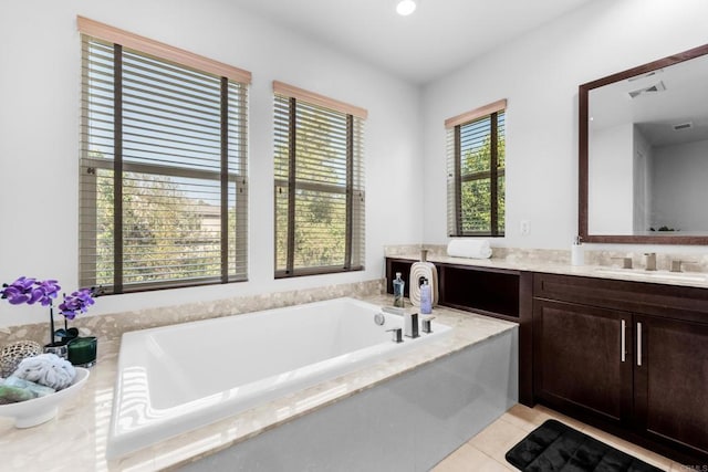 bathroom featuring a wealth of natural light, tile patterned flooring, vanity, and a garden tub