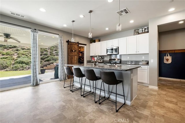 30688 Lone Pine Dr, Menifee, CA 92584 - kitchen with stainless steel microwave, a center island with sink, a kitchen breakfast bar, white cabinetry, and decorative light fixtures