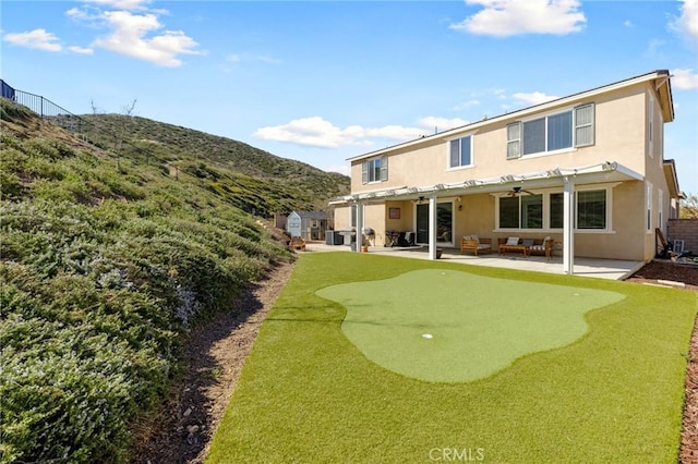 30688 Lone Pine Dr, Menifee, CA 92584 - rear view of house featuring a putting area, stucco siding, a patio, a mountain view, and a ceiling fan