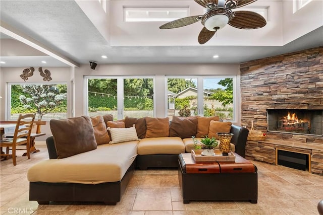 living room with recessed lighting, a stone fireplace, a ceiling fan, and plenty of natural light