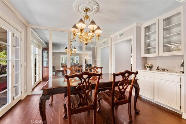 dining room with an inviting chandelier, ornamental molding, dark wood-style flooring, and visible vents