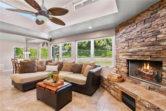 living room with ceiling fan, baseboards, a stone fireplace, and recessed lighting