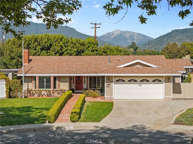 single story home featuring a chimney, a front lawn, driveway, a mountain view, and a garage