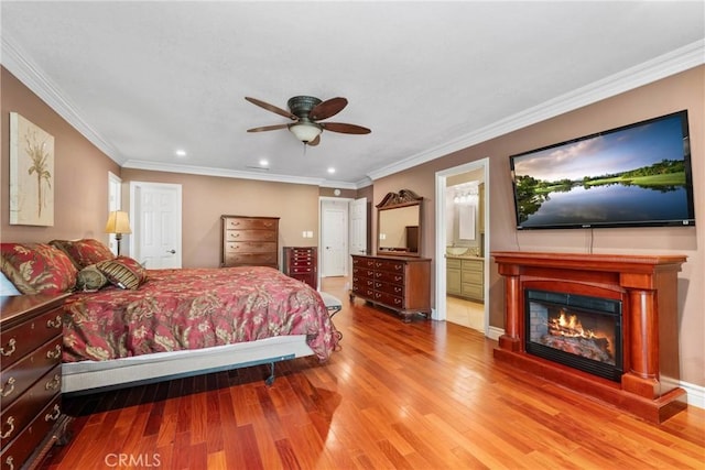 bedroom with a glass covered fireplace, wood finished floors, recessed lighting, and ornamental molding