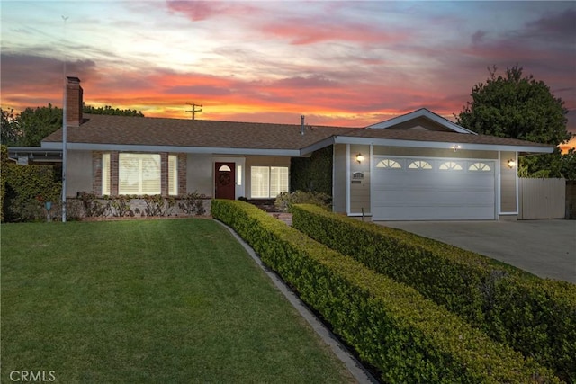 view of front of house featuring driveway, a chimney, a front yard, and a garage
