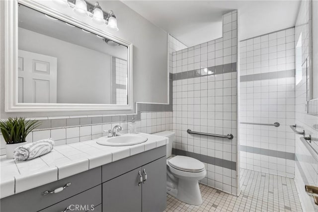 full bathroom featuring tile patterned flooring, toilet, vanity, tile walls, and tiled shower