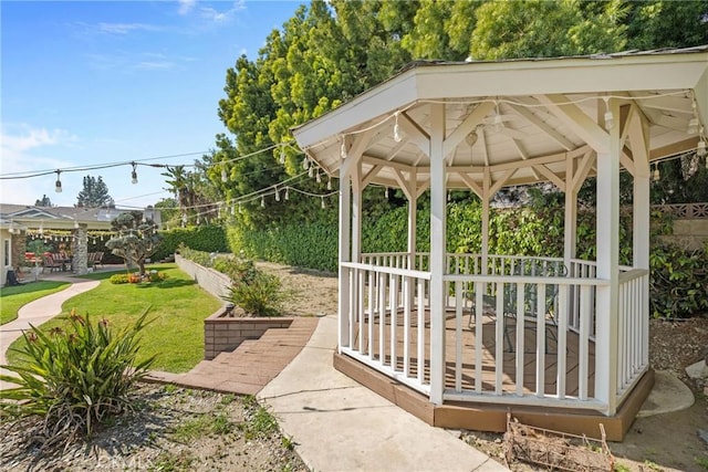 view of property's community with fence, a lawn, and a gazebo