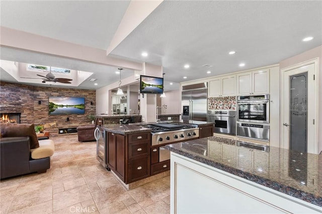 kitchen with dark brown cabinets, a skylight, open floor plan, a warming drawer, and appliances with stainless steel finishes