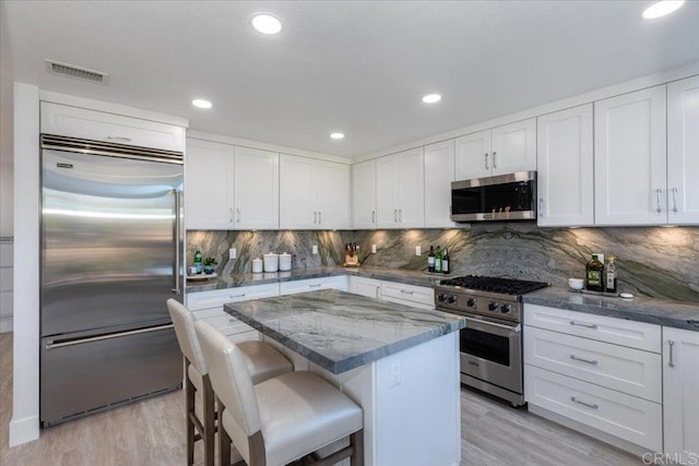 6341 Caminito Del Pastel, San Diego, CA 92111 - kitchen featuring visible vents, a center island, white cabinetry, light wood finished floors, and premium appliances