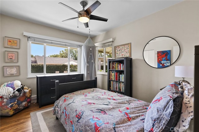 bedroom featuring ceiling fan, multiple windows, and wood finished floors